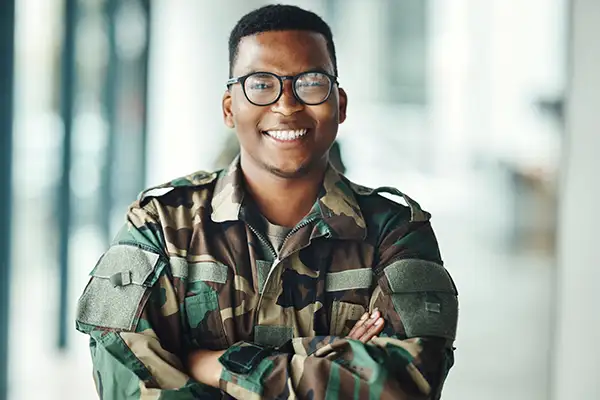 Smiling soldier in military uniform with arms crossed