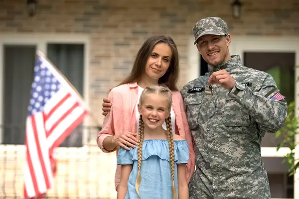 US military man with happy family standing in front of house