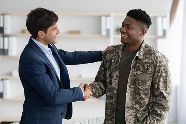 Man in suit shaking hand of man in military uniform