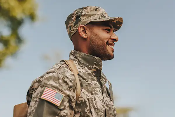 Happy young soldier in US military uniform standing outside