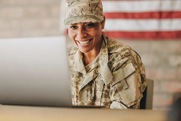 Smiling soldier in US military uniform using laptop