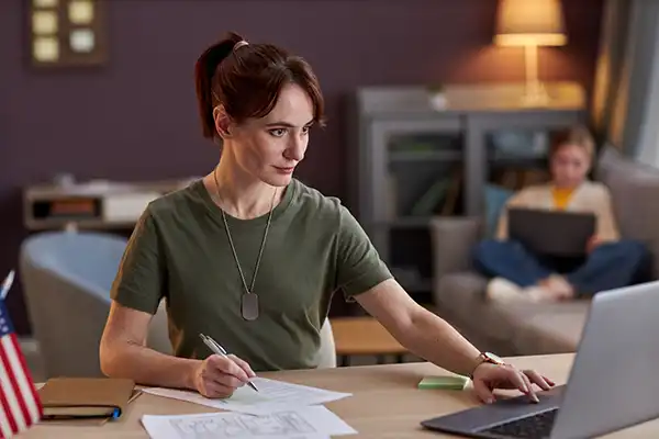 Young military woman using laptop and working at desk in office