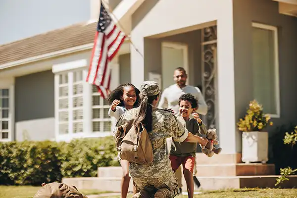 Soldier embracing children on homecoming outside of house