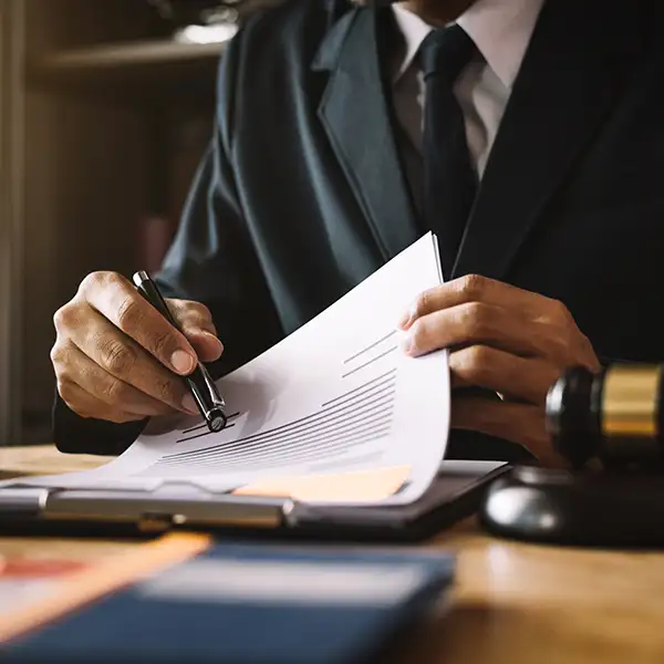 Man in suit pointing to papers on clipboard with pen